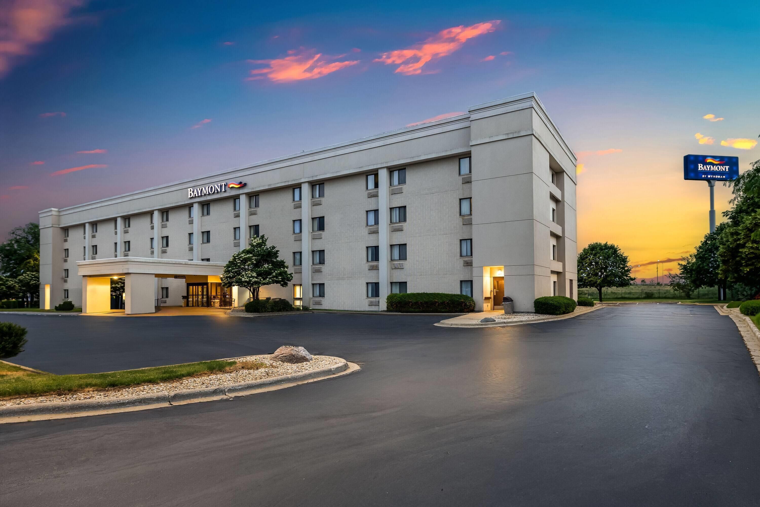 A large, multi-story hotel with a prominent 'Baymont' sign, a spacious parking lot, and a well-maintained landscape.