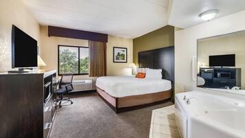 A hotel room with a bed, a desk, a chair, a large window, a bathroom with a bathtub, and a television.