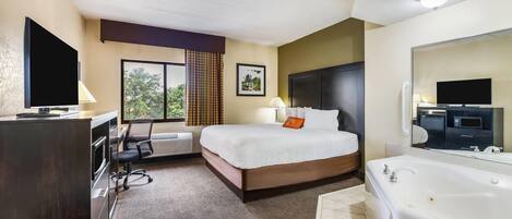 A hotel room with a bed, a desk, a chair, a large window, a bathroom with a bathtub, and a television.
