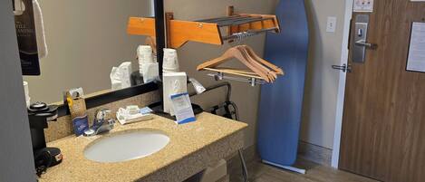 A bathroom with a granite countertop sink, a mirror, a towel rack, and a wooden door.