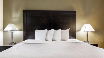A hotel room with a large bed, two bedside tables with lamps, and a dark headboard.