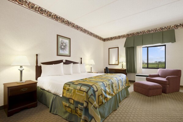 Habitación de hotel con una cama grande, dos mesitas de noche con lámparas, una silla y una ventana con vistas al exterior.