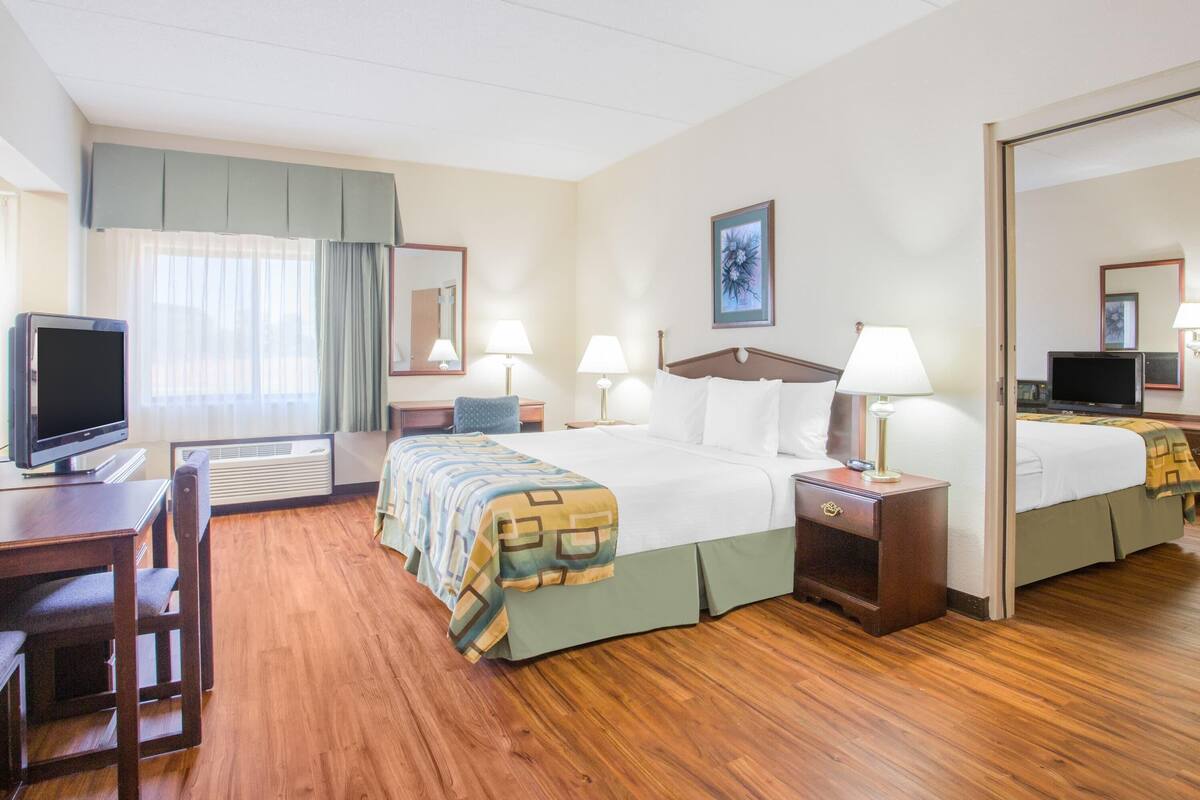 A hotel room with a large bed, two bedside tables with lamps, a desk with a television, and a chair.