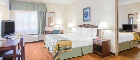 A hotel room with a large bed, two bedside tables with lamps, a desk with a television, and a chair.