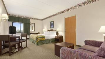 A hotel room with a bed, a desk, a chair, a sofa, and a television.