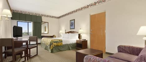 Una habitación de hotel con cama, escritorio, silla, sofá y televisor.