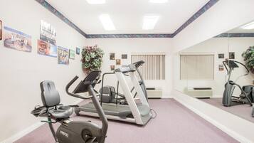 Un gimnasio con cintas de correr, elíptica y bicicleta estática.
