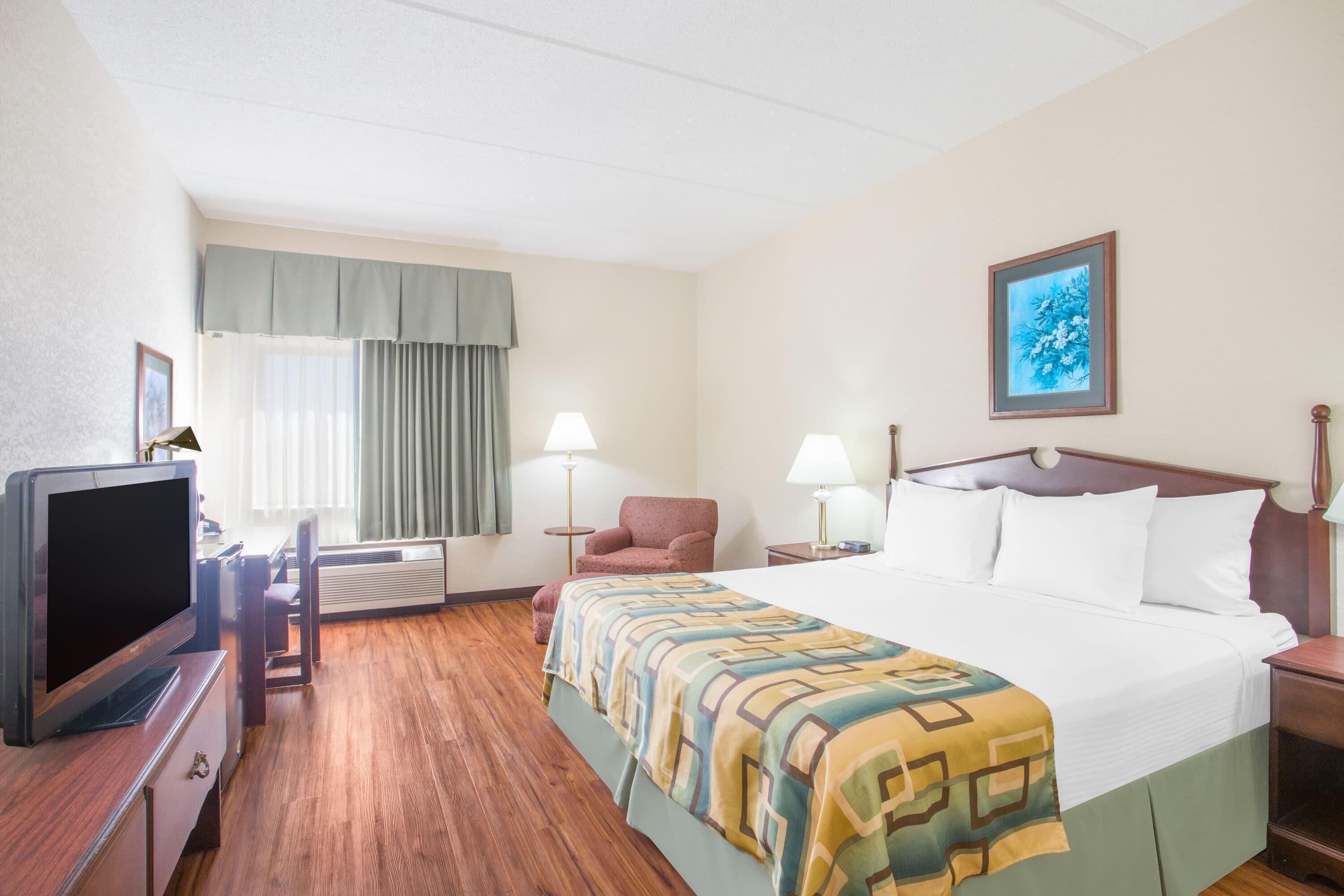 A hotel room with a bed, a television, a chair, and a desk.