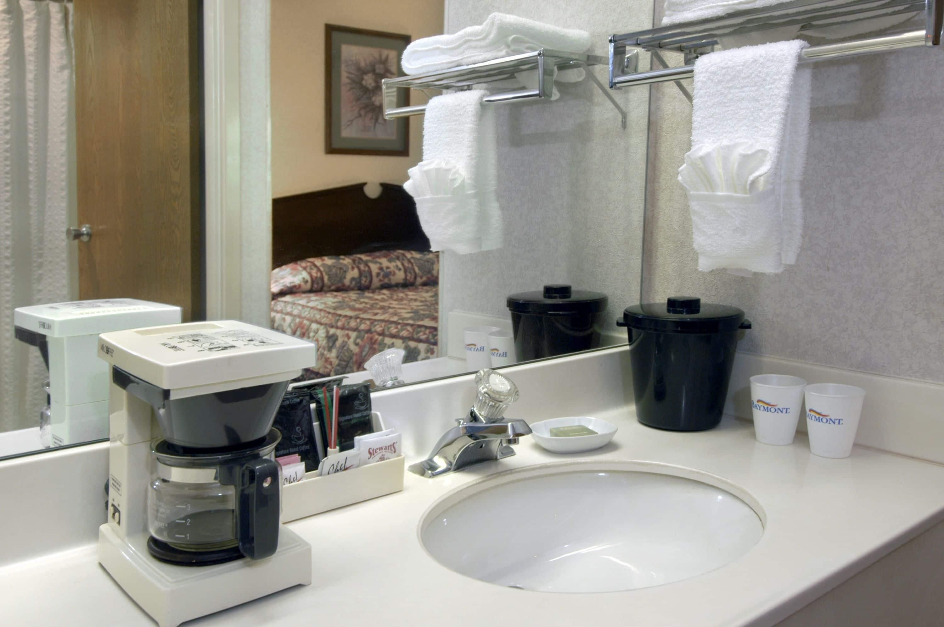 Ein Hotelbad mit einer Kaffeemaschine, einem Waschbecken und einem Handtuchhalter.