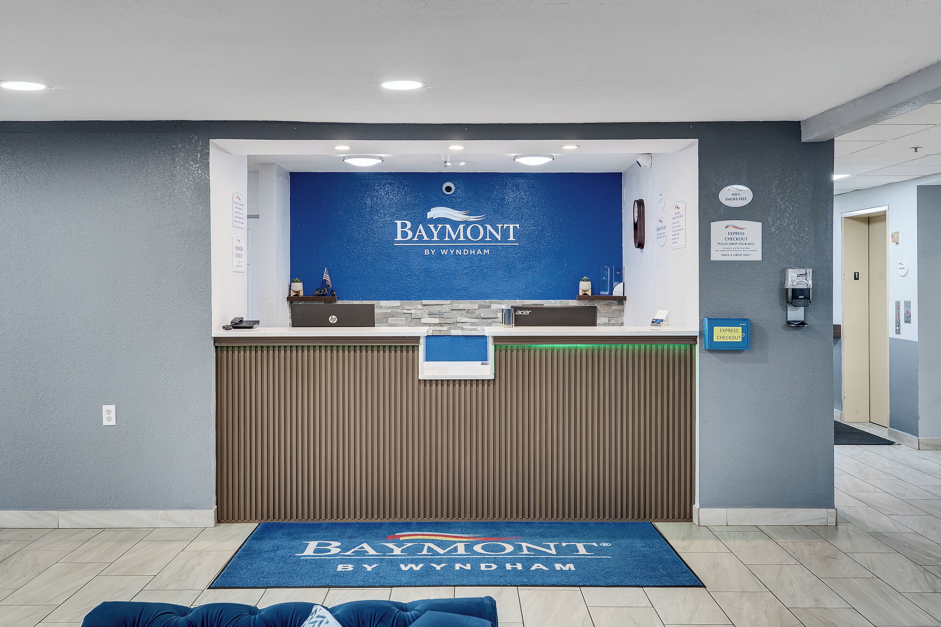 Un'area reception con parete blu, una scrivania e un tappeto blu con il nome dell'hotel.