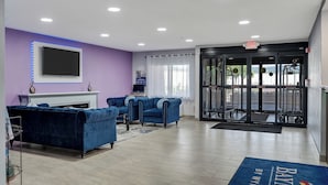 A lobby with a reception desk, blue sofas, a flat-screen TV, and an exit door. - Baymont by Wyndham La Crosse/Onalaska (Onalaska)