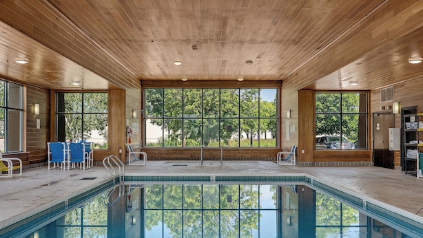 A pool area with wooden ceiling, large windows, and a view of trees. - Baymont by Wyndham La Crosse/Onalaska (Onalaska)