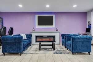 Una sala de estar con chimenea, dos sofás azules y un televisor de pantalla plana sobre la chimenea.