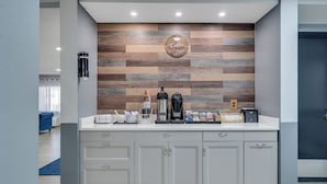 A modern coffee bar with a wooden wall backdrop, a coffee machine, and various coffee accessories. - Baymont by Wyndham La Crosse/Onalaska (Onalaska)