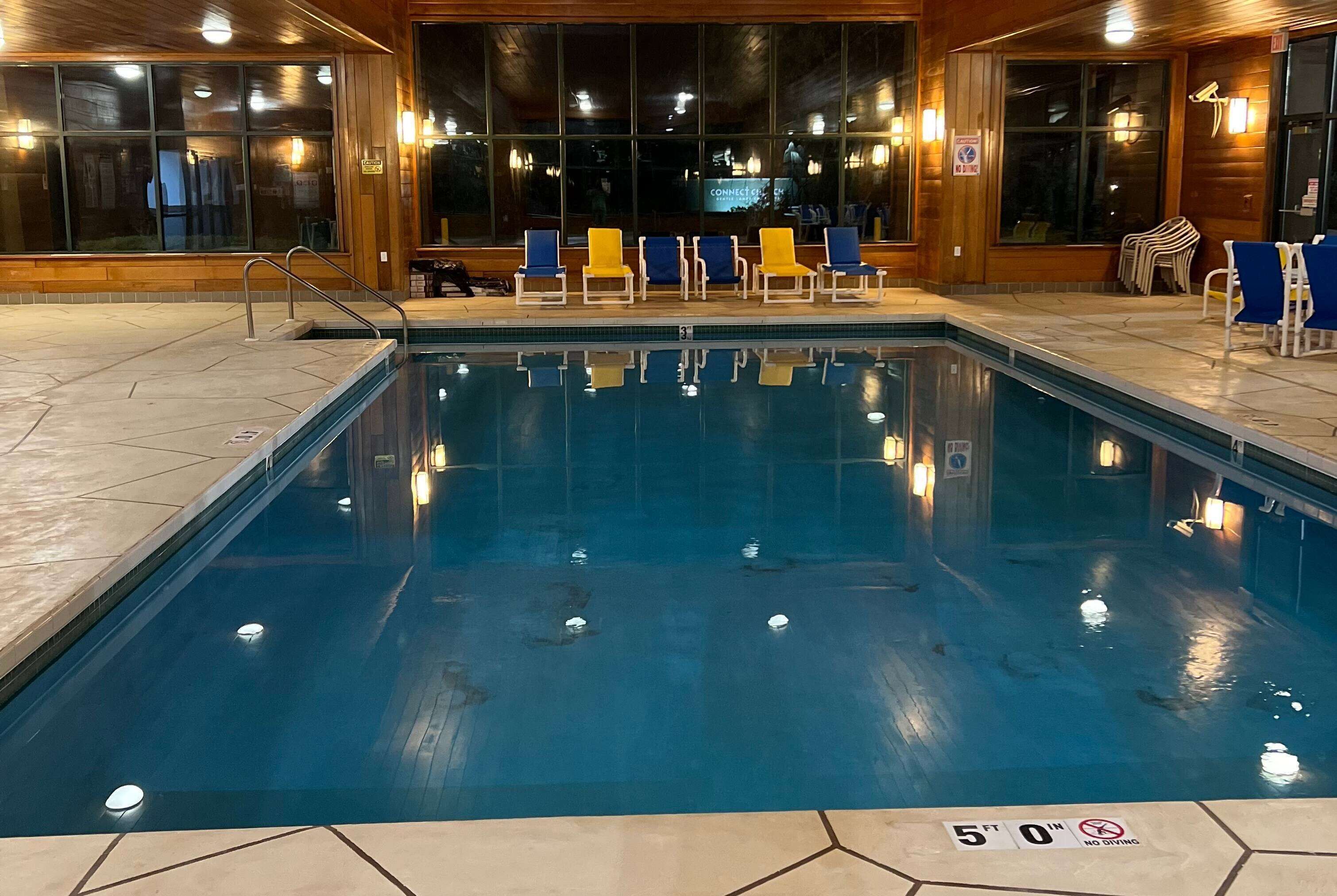 Una piscina interior con indicador de profundidad de 1.5 metros, rodeada de sillas de descanso y un interior de madera.
