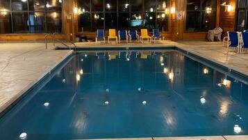 Una piscina interior con indicador de profundidad de 1.5 metros, rodeada de sillas de descanso y un interior de madera.