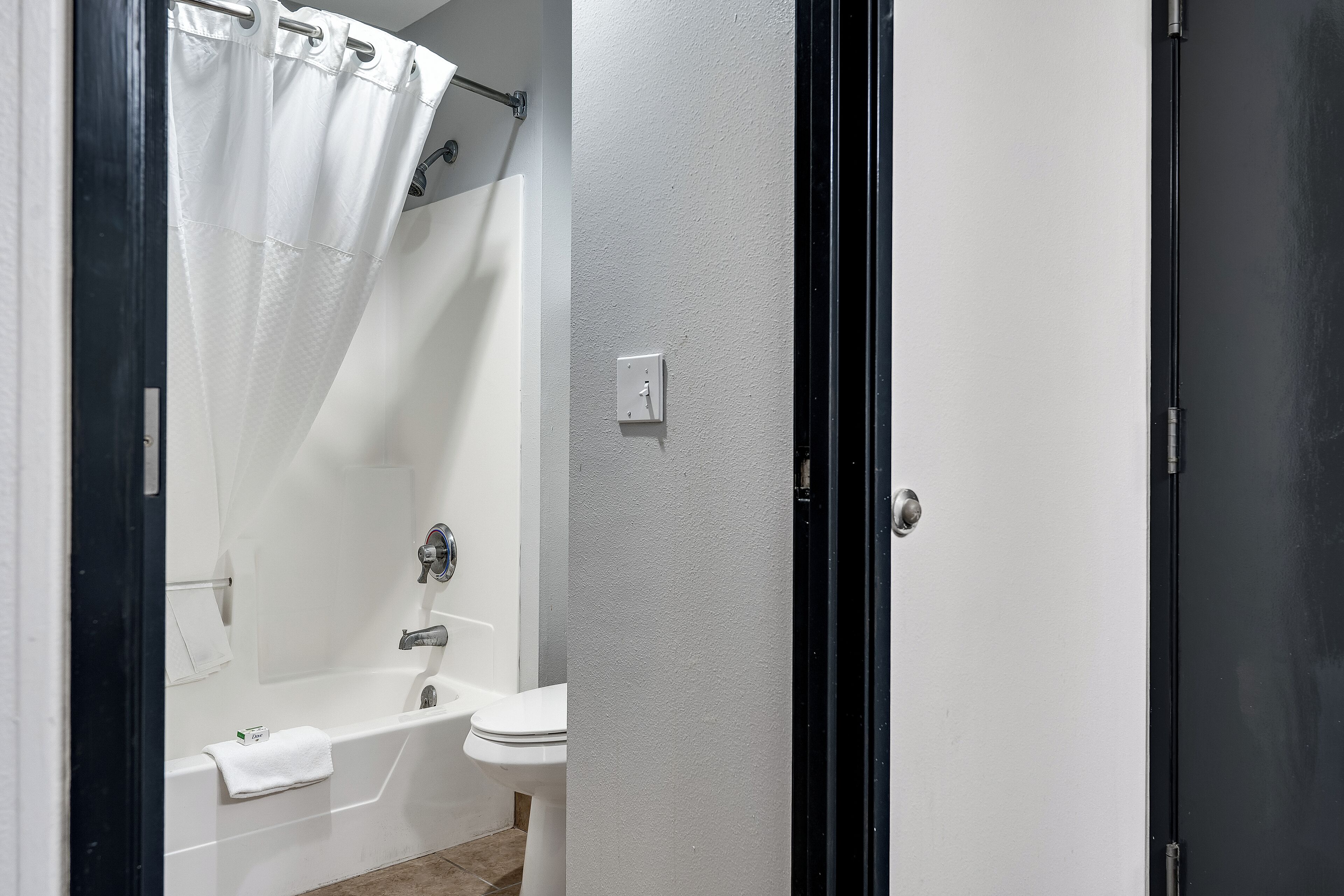 A bathroom with a bathtub, toilet, and a shower curtain.