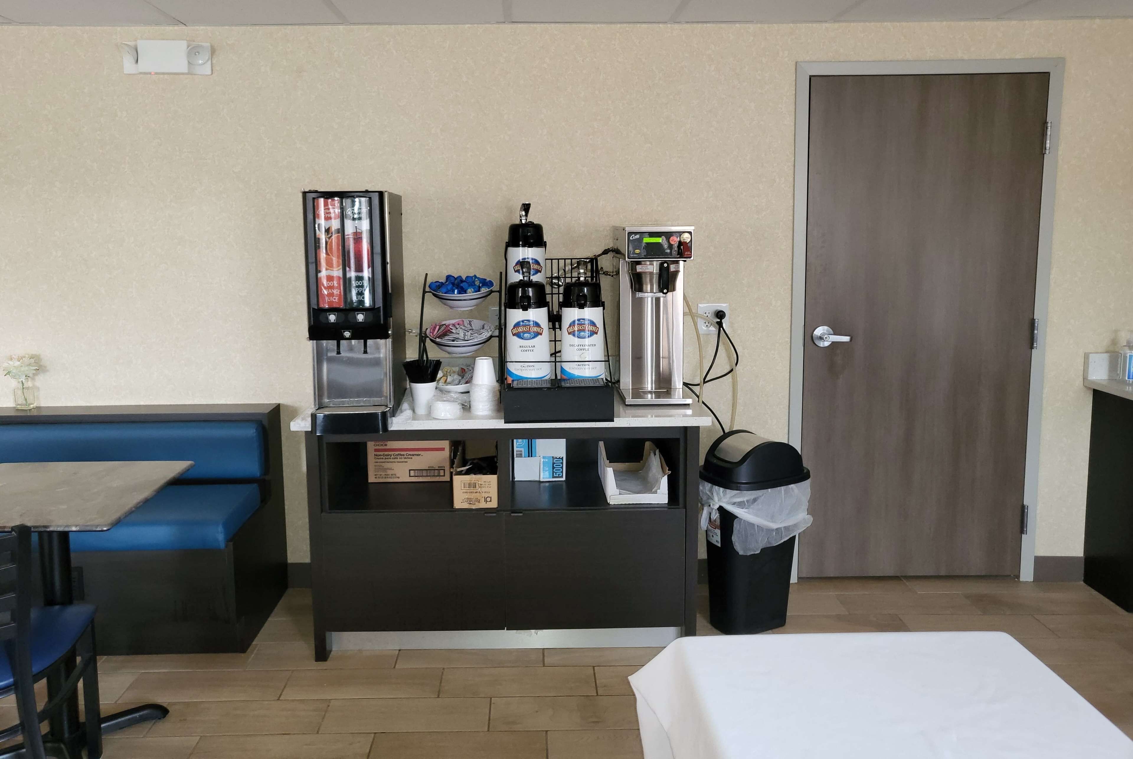 A hotel room with a kitchenette, a coffee machine, a microwave, and a trash bin.