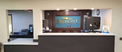 A reception desk with a 'Baymont' sign, a 'No Smoking' sign, and a 'Best' award sign.