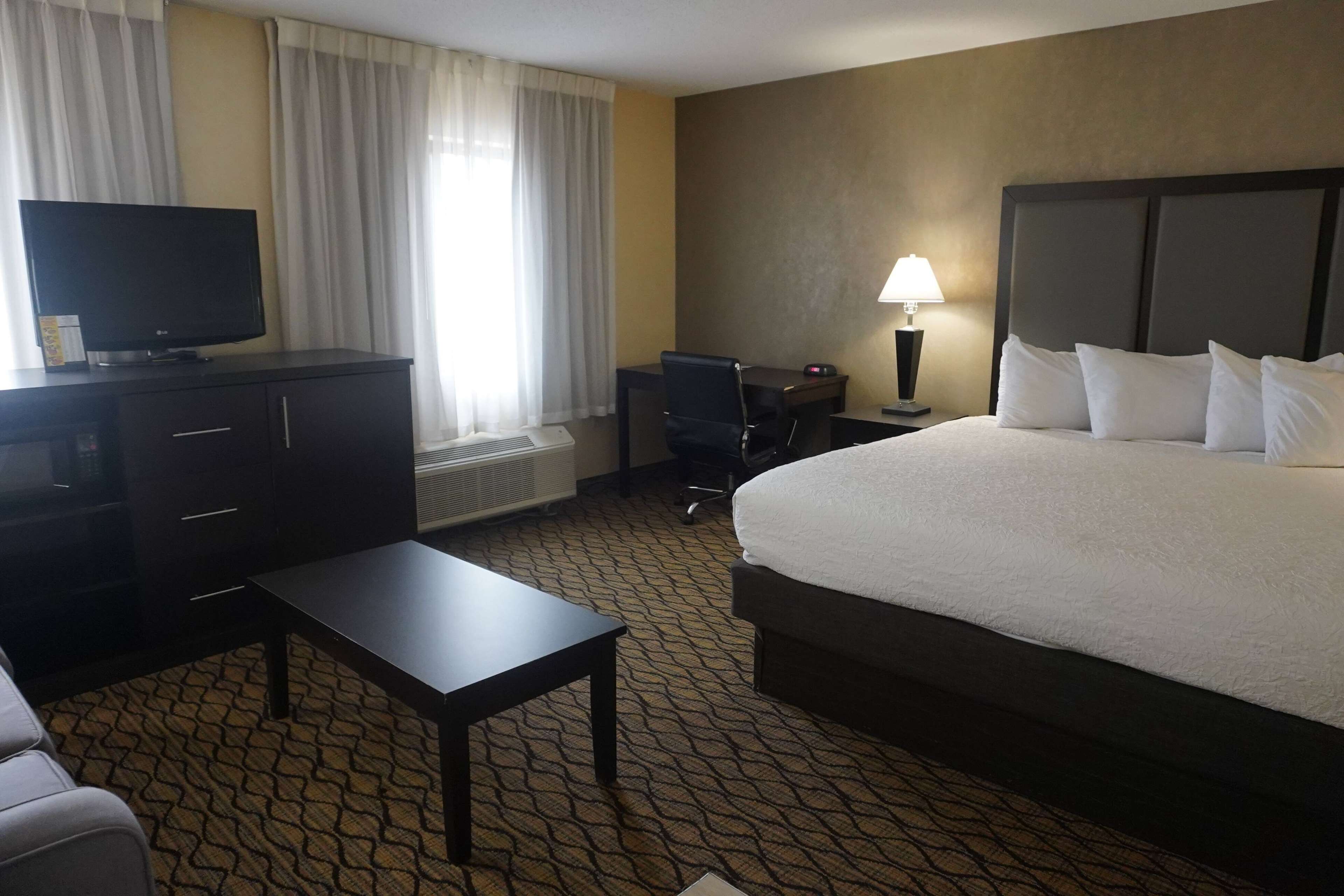 A hotel room with a bed, a desk, a television, and a lamp.