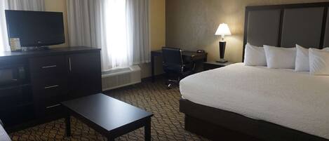 A hotel room with a bed, a desk, a television, and a lamp.