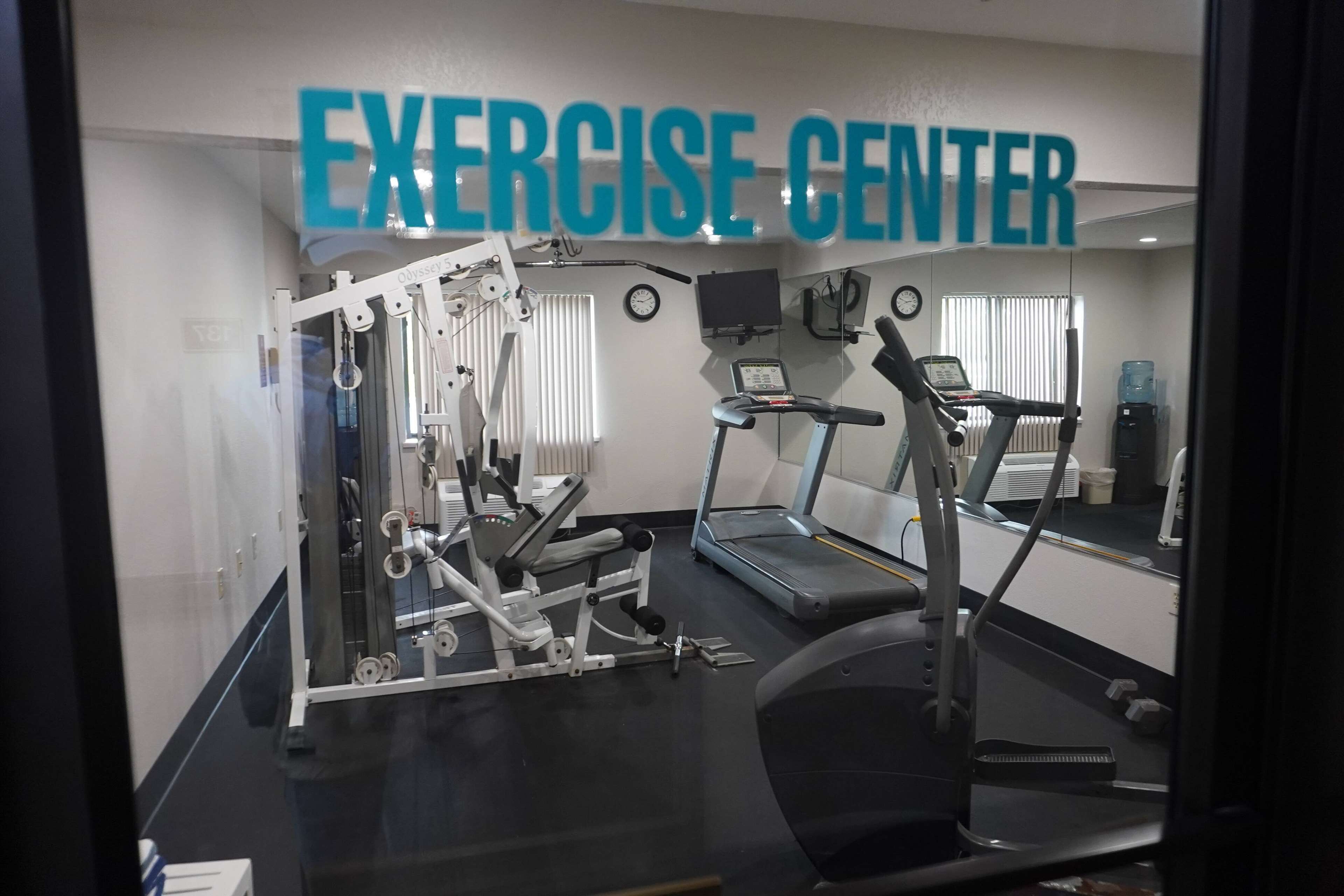 An exercise center with a treadmill, elliptical, and weight machines.