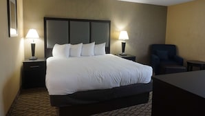 Habitación de hotel con una cama grande, dos lámparas de noche, una silla y una mesita.