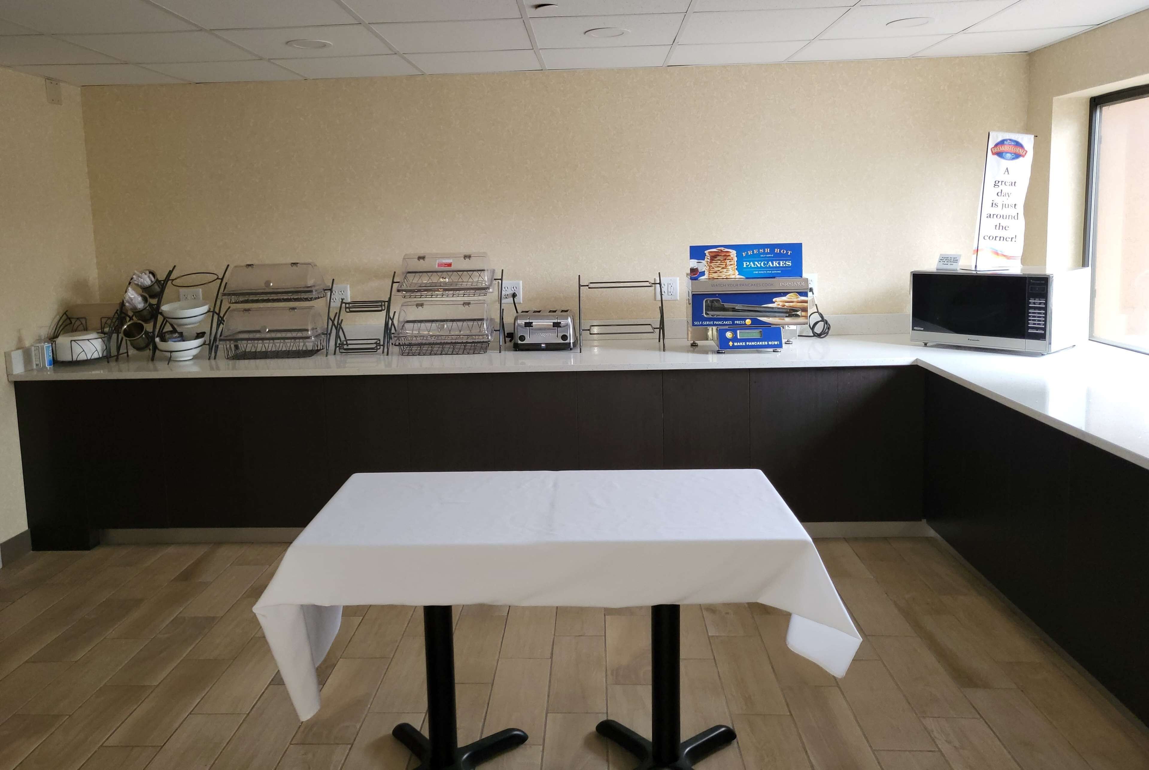 A counter with a microwave, toaster, and a sign for pancakes.