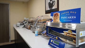 A self-serve pancake station with a sign indicating fresh hot pancakes, a popcorn maker, and a water dispenser.