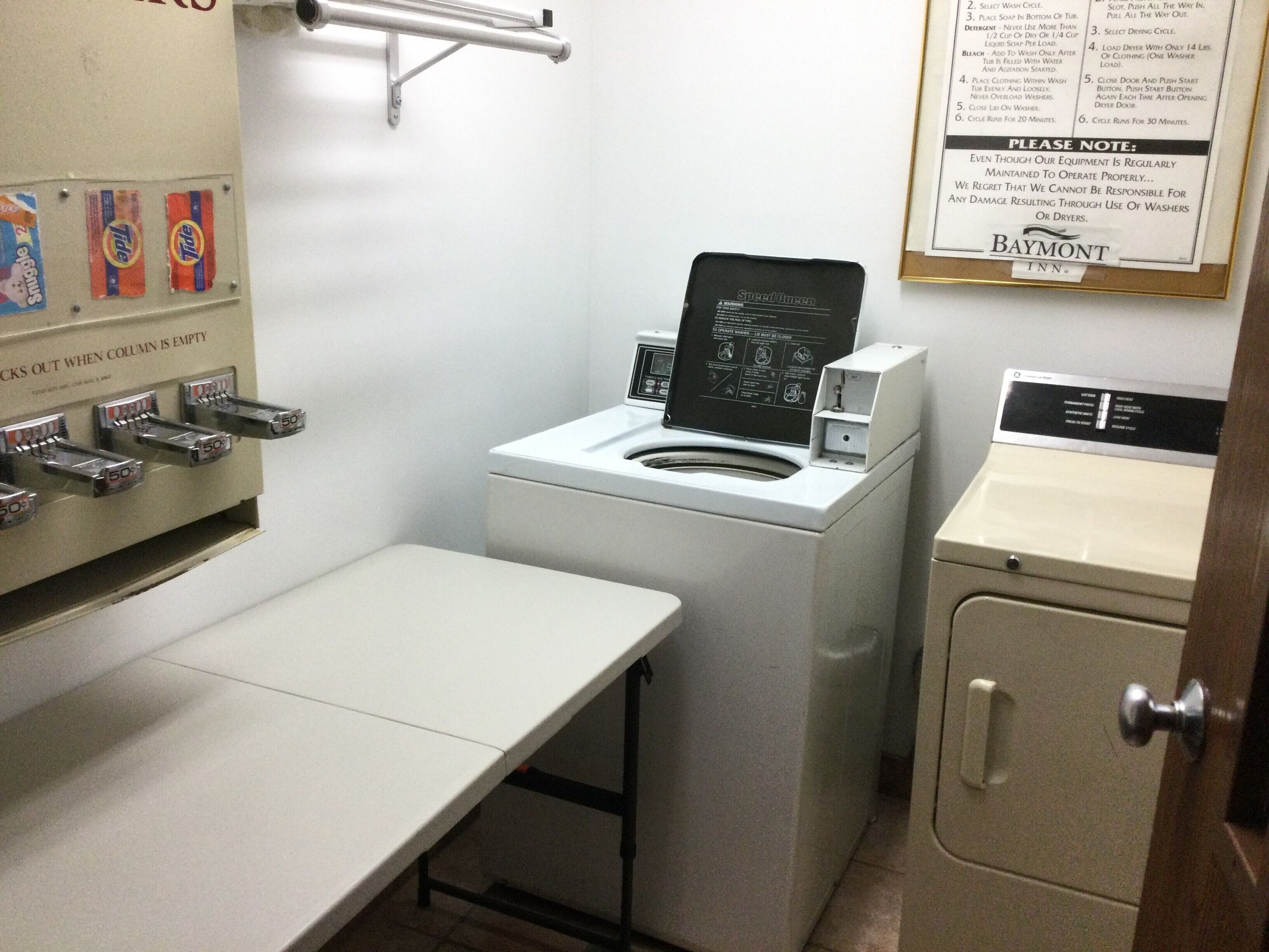 A laundry area with a washing machine, a drying machine, and a sink. There are Tide detergent dispensers on the wall.