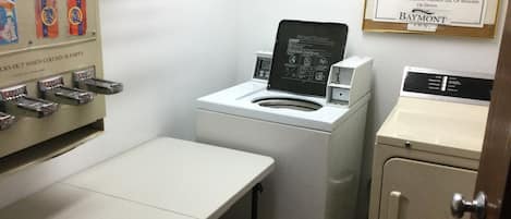 A laundry area with a washing machine, a drying machine, and a sink. There are Tide detergent dispensers on the wall.
