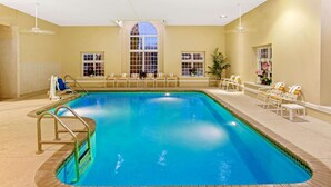 Una piscina interior con agua cristalina, rodeada de sillones de descanso y una tumbona.