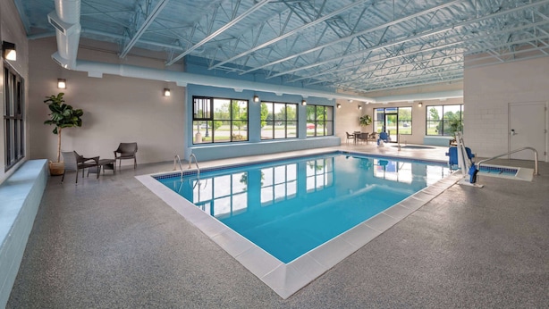 En indendørs swimmingpool med gennemsigtigt tag, store vinduer og siddeområder.