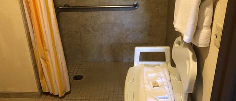 A bathroom with a shower, a grab bar, a toilet, and a towel rack.