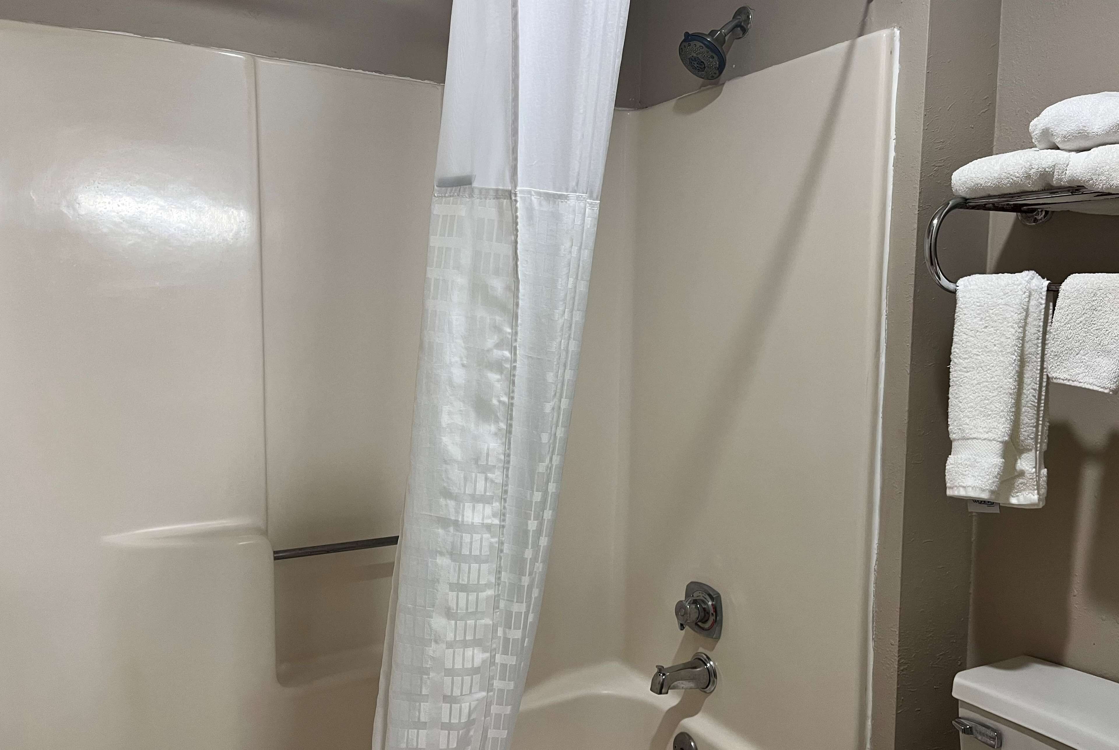 Une salle de bain avec un rideau de douche, un porte-serviettes avec des serviettes et des toilettes.