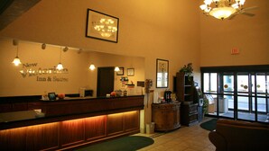 Uma área de recepção com balcão de madeira, um candelabro e uma placa para New Victorian Inn & Suites.