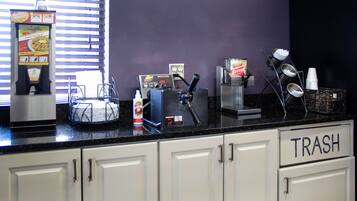 A kitchen counter with a waffle maker, a coffee machine, and a trash bin.