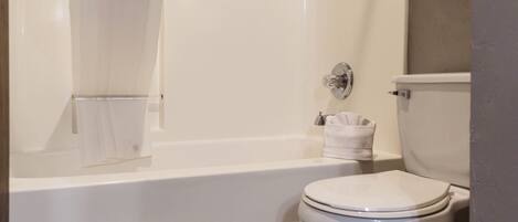 A bathroom with a toilet, a bathtub, and a shower curtain.