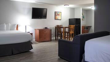 Habitación de hotel con cama, sofá, escritorio con silla, televisor y microondas.