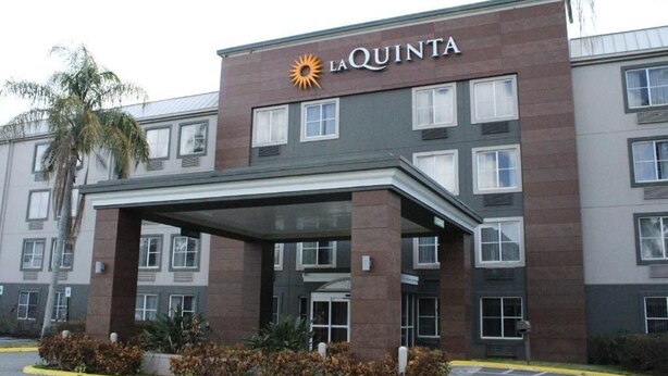 A La Quinta hotel with a covered entrance, multiple windows, and a palm tree in the foreground. - La Quinta Inn & Suites by Wyndham Lakeland East (Lakeland)