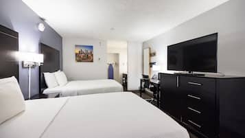 Habitación de hotel con dos camas, un escritorio, un televisor y un cuadro en la pared.