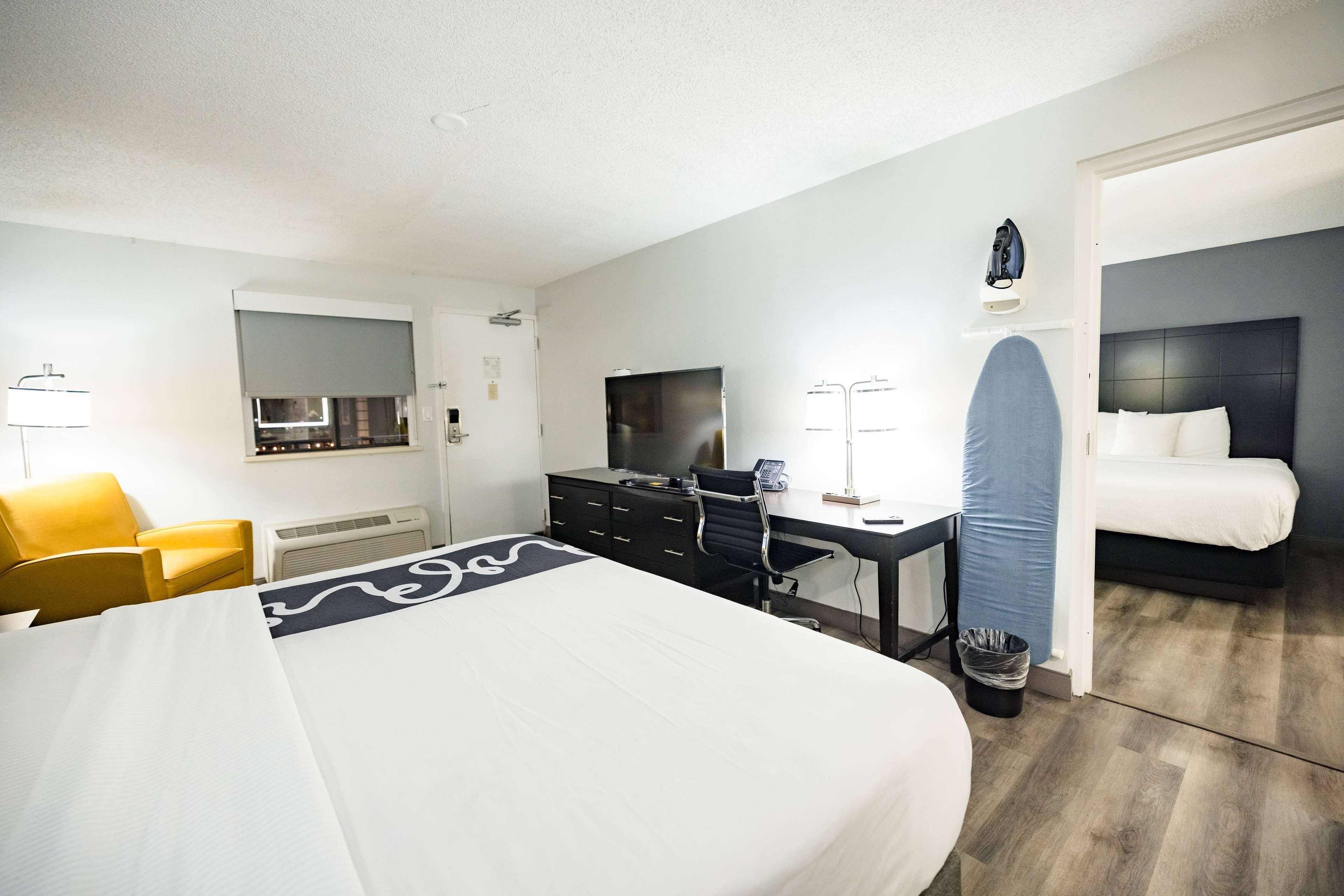 Una habitación de hotel con cama, escritorio, silla, televisión y baño.