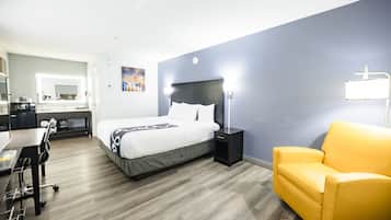 Quarto de hotel com cama, escrivaninha, cadeira e sofá.