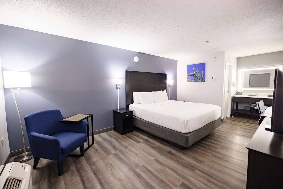 Una habitación de hotel con cama, escritorio, silla y lámpara.