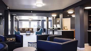 A modern lobby with seating areas, a reception desk, and a clock on the wall.