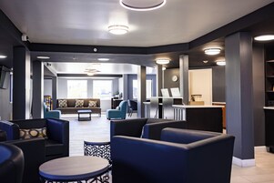 A modern lobby with seating areas, a reception desk, and a clock on the wall.