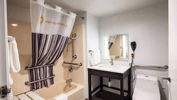 A bathroom with a bathtub, a shower curtain, a toilet, a sink, and a mirror.