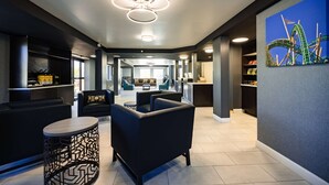Un moderno vestíbulo de hotel con una zona de estar central, una cocina y un comedor.