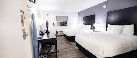 A hotel room with two beds, a desk, and a chair.