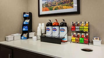 Una estación de café con vasos desechables, dispensador de café y diversas opciones de sabor.